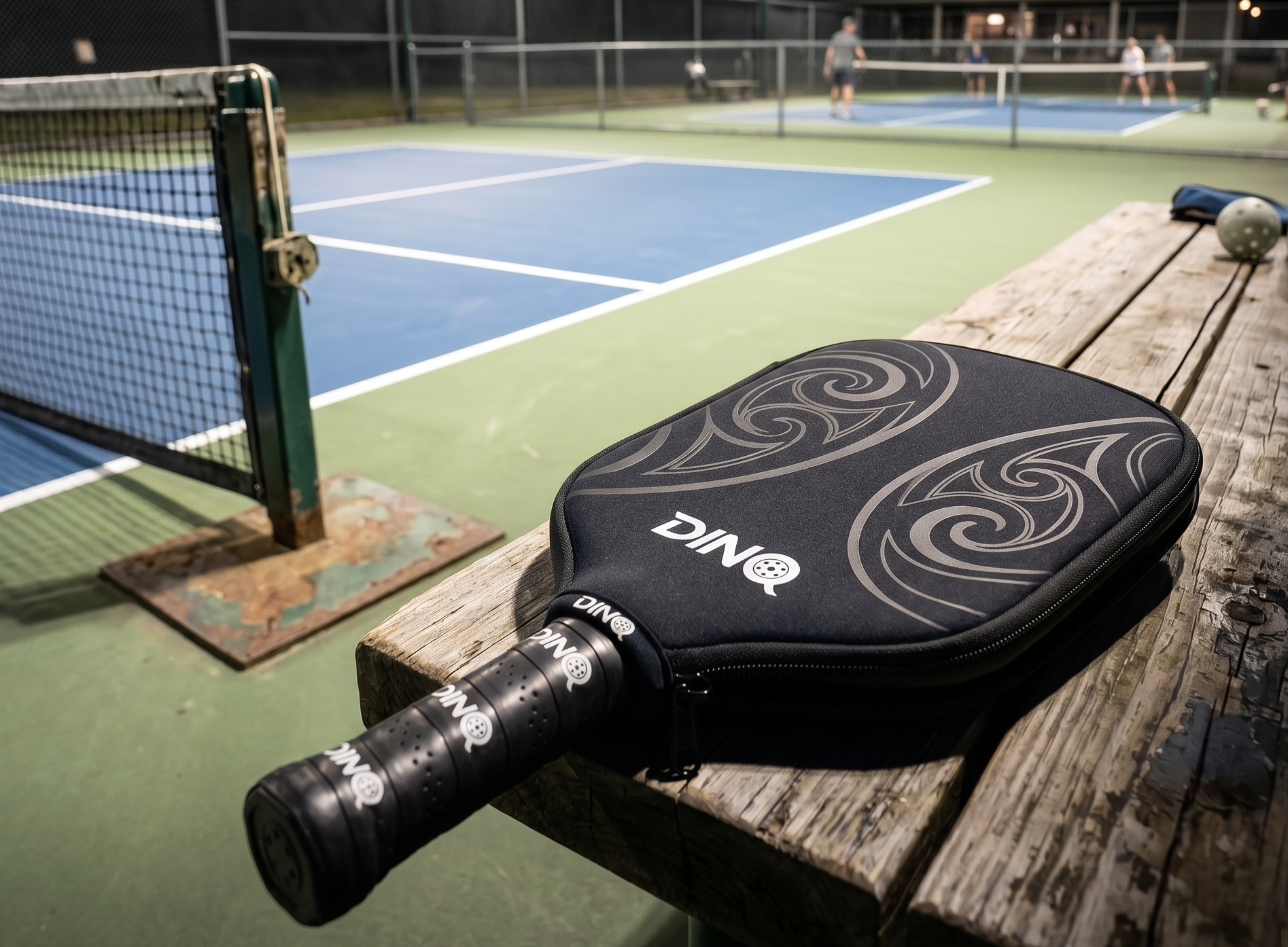 DINQ premium paddle cover on a bench at an outdoor pickleball court